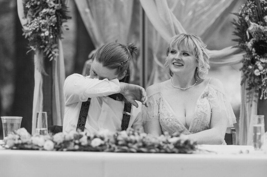 Emotional black and white image of groom tearing up during wedding speeches