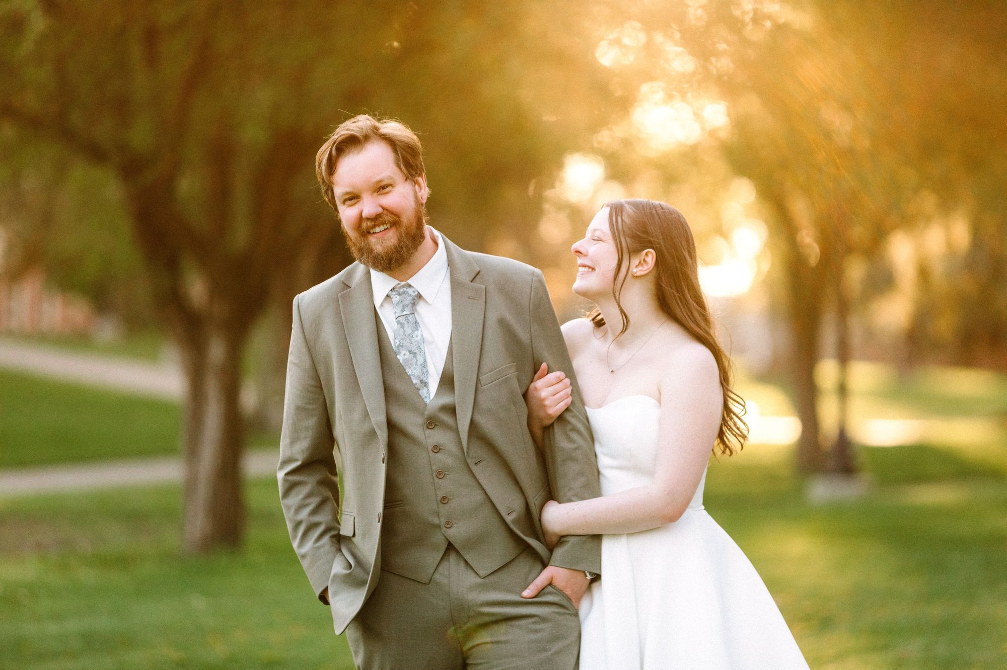 Couple walking together in sun soaked skies with their arms linked together